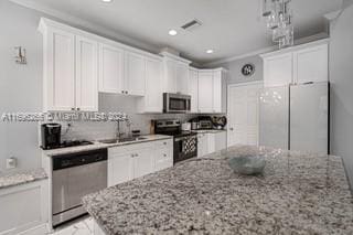 kitchen featuring light stone countertops, sink, white cabinets, and appliances with stainless steel finishes