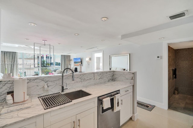 kitchen featuring light stone countertops, sink, light tile patterned floors, stainless steel dishwasher, and white cabinets