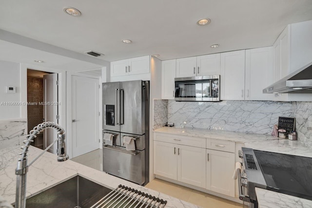 kitchen featuring white cabinets, decorative backsplash, stainless steel appliances, and light stone countertops