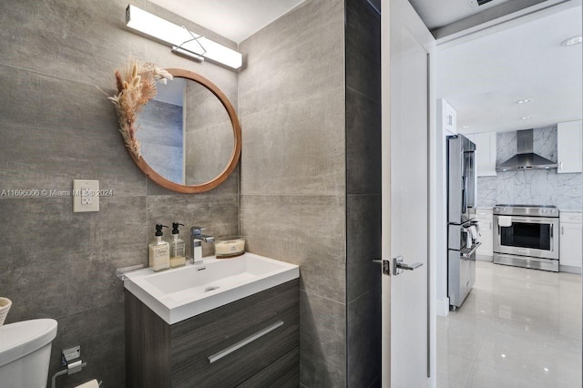 bathroom featuring vanity, toilet, and tile walls