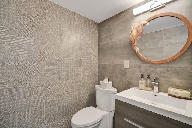 bathroom with vanity, tile walls, and toilet