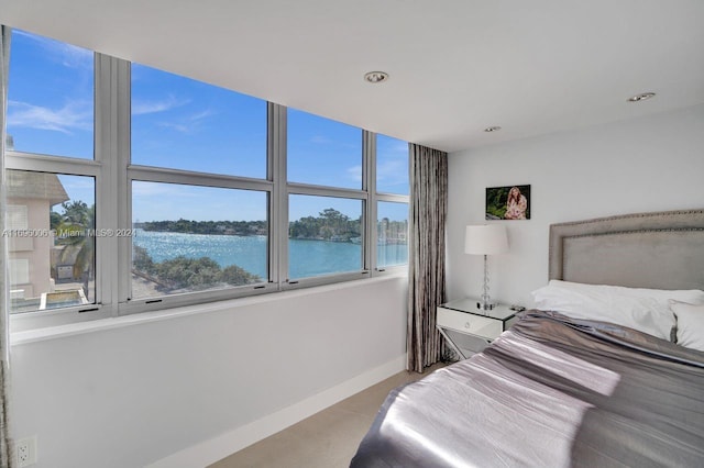 bedroom featuring a water view and light tile patterned floors