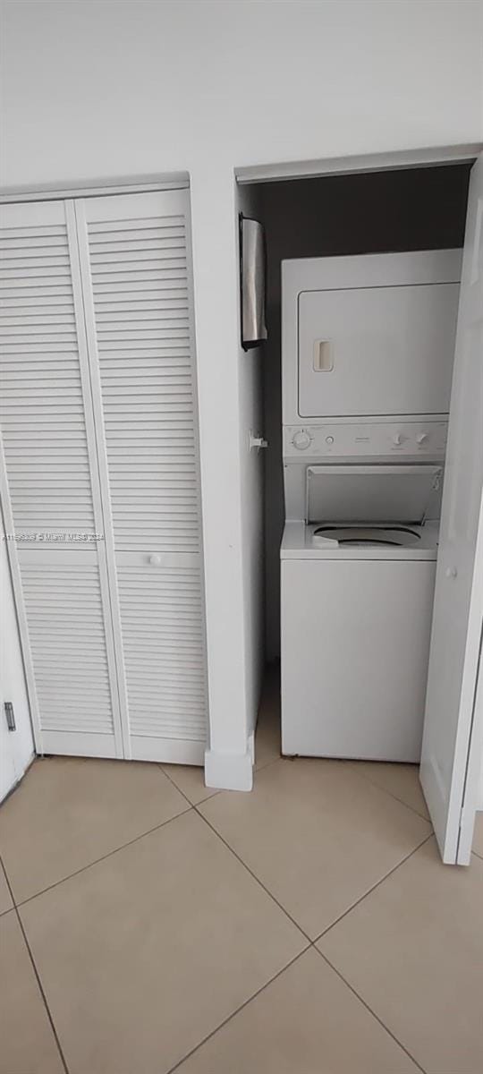 laundry area featuring light tile patterned floors and stacked washer and clothes dryer