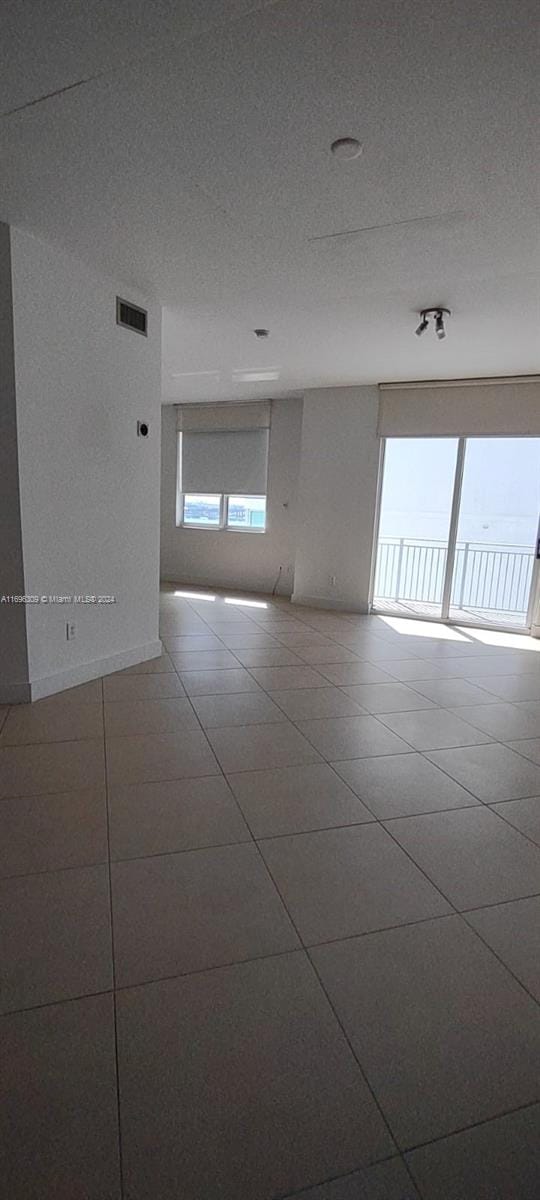 tiled empty room featuring a textured ceiling