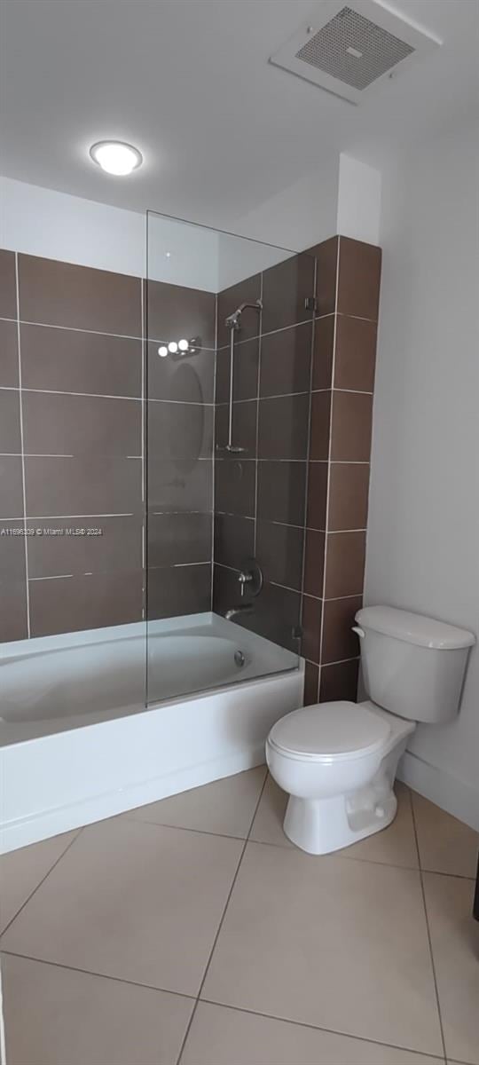 bathroom with toilet, tile patterned floors, and tiled shower / bath