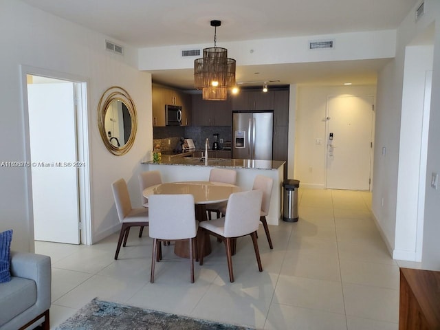 tiled dining space with a notable chandelier and sink