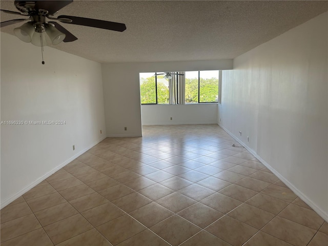 tiled empty room featuring ceiling fan and a textured ceiling