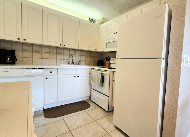 kitchen featuring white appliances, sink, decorative backsplash, a textured ceiling, and white cabinetry