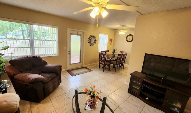 living room with ceiling fan, light tile patterned floors, and a textured ceiling