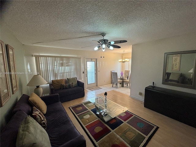 living room with light hardwood / wood-style flooring, ceiling fan with notable chandelier, and a textured ceiling