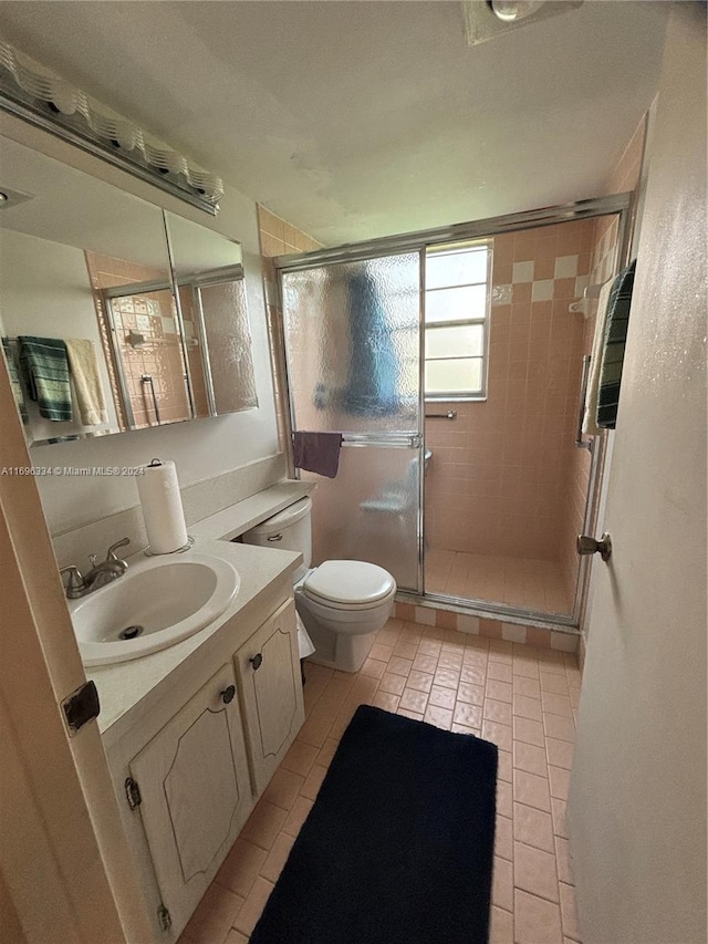 bathroom featuring tile patterned floors, a shower with door, vanity, and toilet