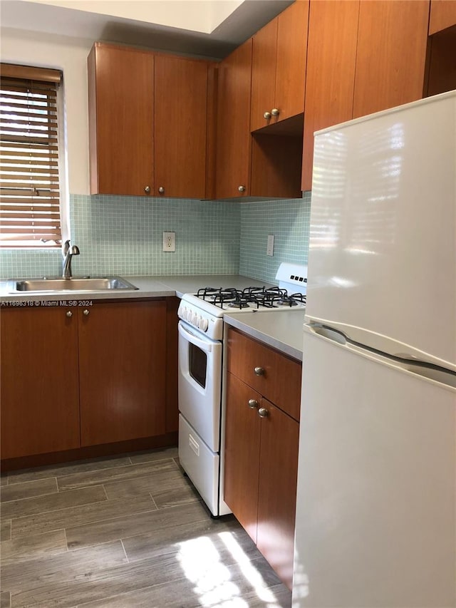 kitchen featuring dark hardwood / wood-style floors, white appliances, sink, and tasteful backsplash