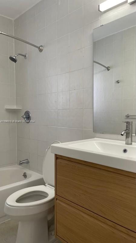 full bathroom featuring vanity, toilet, tile walls, and tiled shower / bath combo