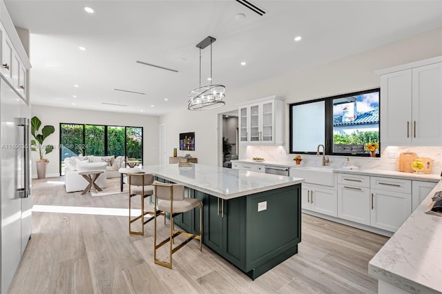 kitchen featuring pendant lighting, a center island, sink, light hardwood / wood-style floors, and white cabinetry