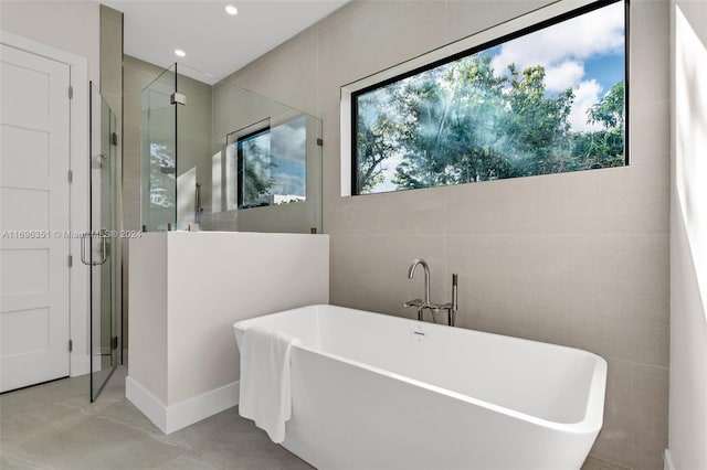 bathroom featuring separate shower and tub, a wealth of natural light, and tile walls