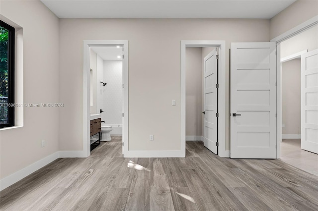 unfurnished bedroom with light wood-type flooring and ensuite bath