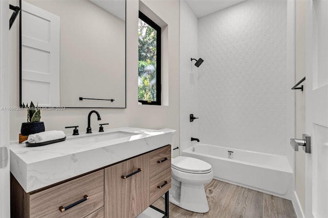 full bathroom with vanity, wood-type flooring, tiled shower / bath combo, and toilet