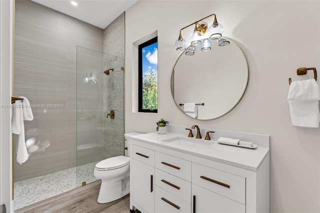 bathroom featuring hardwood / wood-style floors, vanity, toilet, and tiled shower