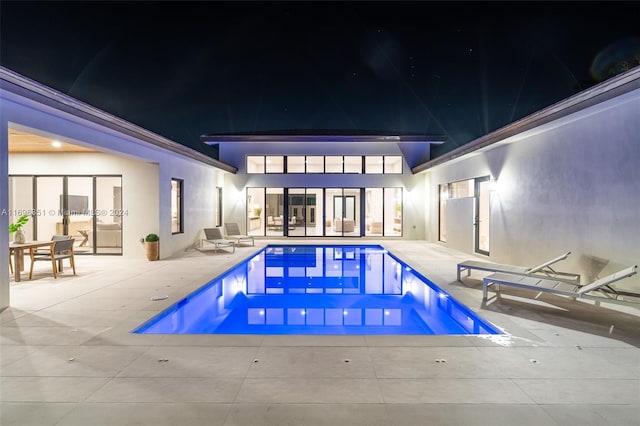 pool at night featuring a patio area