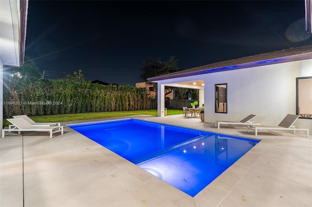 pool at night with a patio area