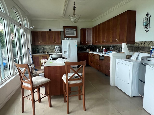 kitchen featuring white refrigerator with ice dispenser, decorative backsplash, hanging light fixtures, and washing machine and clothes dryer