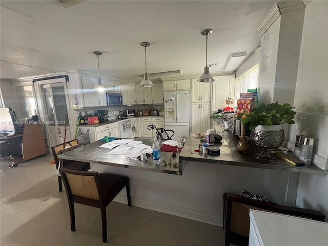 kitchen with white cabinetry, kitchen peninsula, pendant lighting, a kitchen bar, and appliances with stainless steel finishes