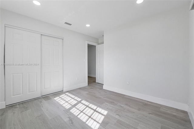 unfurnished bedroom with light hardwood / wood-style flooring and a closet