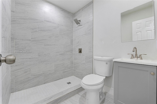 bathroom with vanity, toilet, and a tile shower