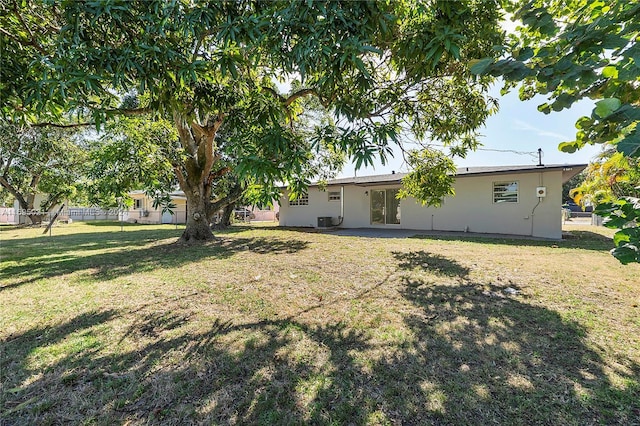 rear view of house featuring central AC and a lawn