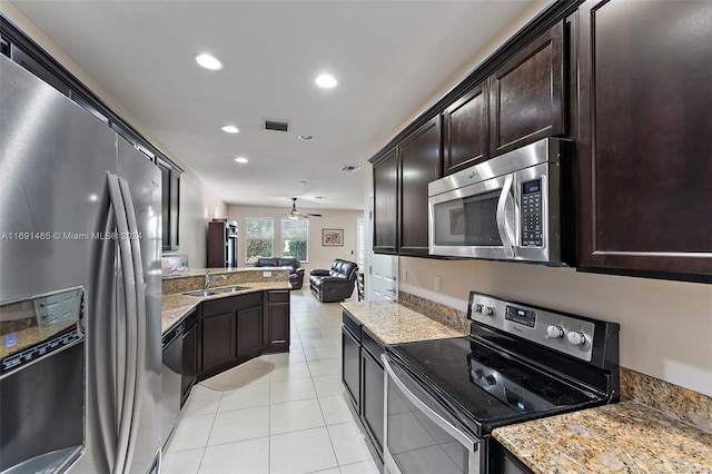 kitchen with ceiling fan, sink, light stone countertops, and appliances with stainless steel finishes