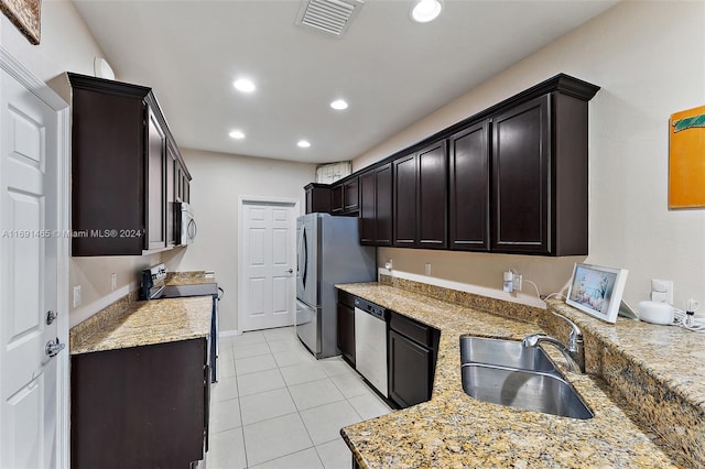 kitchen with sink, stainless steel appliances, light stone counters, dark brown cabinets, and light tile patterned floors