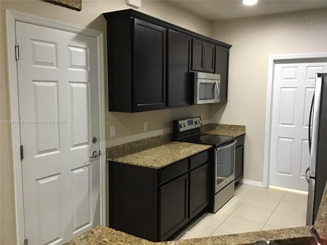 kitchen with light stone countertops, light tile patterned floors, and appliances with stainless steel finishes