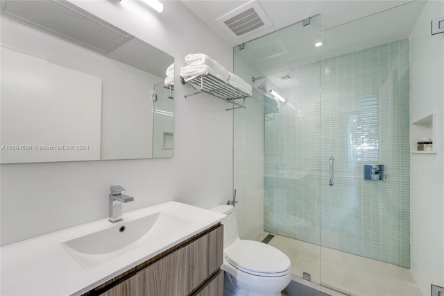 bathroom featuring vanity, a shower with shower door, and toilet