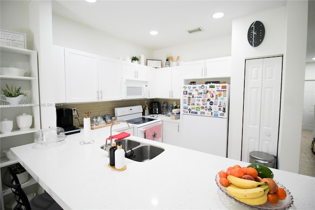 kitchen with decorative backsplash, a breakfast bar, white appliances, sink, and white cabinetry