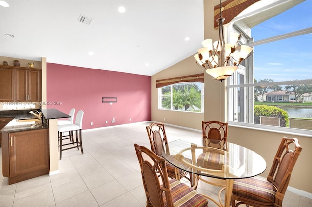 dining room with sink, light tile patterned floors, a chandelier, vaulted ceiling, and a water view