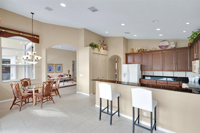 kitchen with a chandelier, pendant lighting, white appliances, and light tile patterned flooring