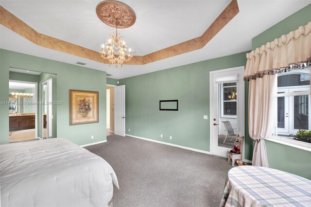 bedroom with carpet flooring, a tray ceiling, and a chandelier