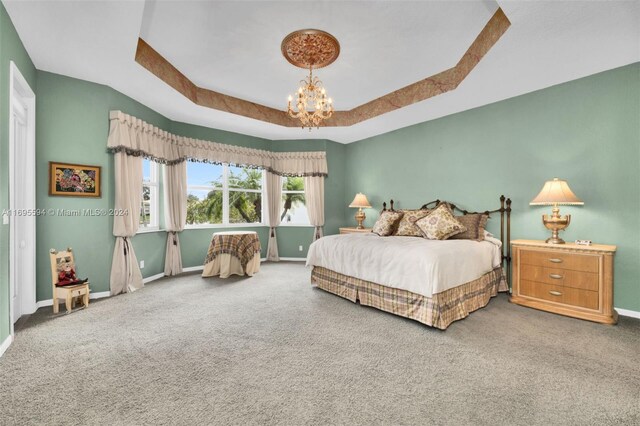 bedroom with carpet flooring, a raised ceiling, and a notable chandelier