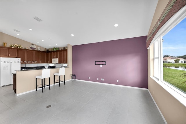 kitchen featuring plenty of natural light, a kitchen bar, white appliances, and kitchen peninsula