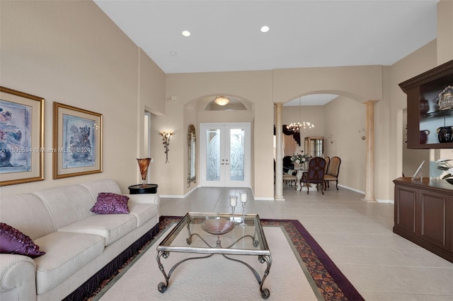 living room with ornate columns, french doors, light tile patterned floors, and a notable chandelier