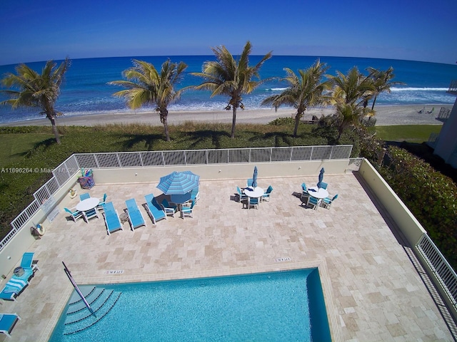 view of pool featuring a patio area, a water view, and a view of the beach