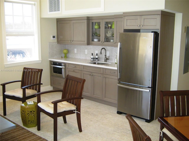 kitchen featuring decorative backsplash, stainless steel appliances, gray cabinets, and sink