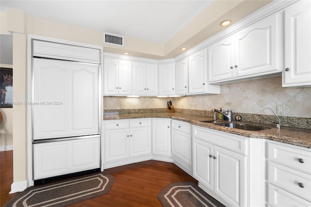 kitchen featuring white cabinetry, sink, dark hardwood / wood-style flooring, backsplash, and dark stone counters