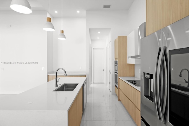 kitchen with sink, hanging light fixtures, stainless steel fridge, a kitchen island with sink, and black electric stovetop