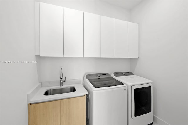 clothes washing area featuring sink, cabinets, and independent washer and dryer