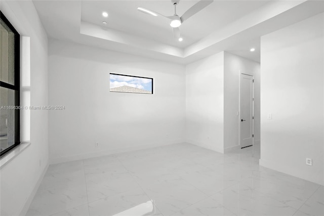 unfurnished room featuring a raised ceiling and ceiling fan