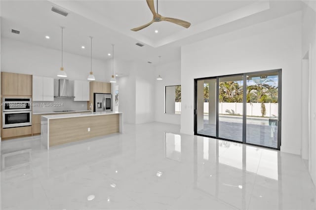 kitchen featuring appliances with stainless steel finishes, ceiling fan, sink, wall chimney range hood, and white cabinetry