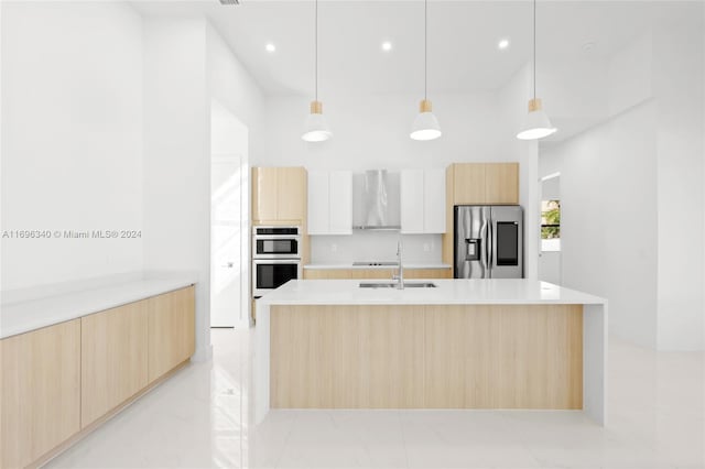 kitchen with pendant lighting, white cabinets, wall chimney exhaust hood, light brown cabinetry, and stainless steel appliances