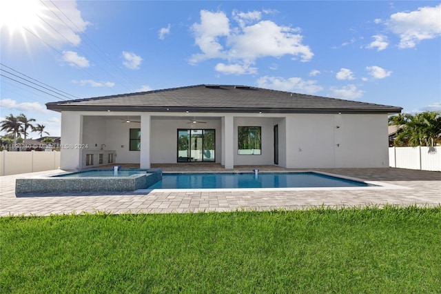 rear view of property with a swimming pool with hot tub, ceiling fan, and a yard