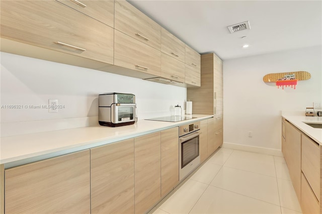 kitchen featuring stainless steel oven, light brown cabinets, black electric cooktop, light tile patterned flooring, and extractor fan